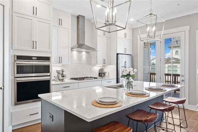 1104 Thomas St, Woodstock, GA 30188 - kitchen featuring wall chimney exhaust hood, appliances with stainless steel finishes, a chandelier, light wood-style flooring, and white cabinetry