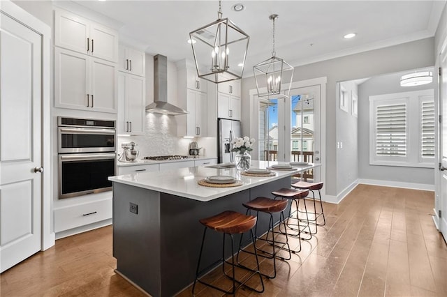 1104 Thomas St, Woodstock, GA 30188 - kitchen with wall chimney range hood, stainless steel appliances, a center island, white cabinetry, and light countertops