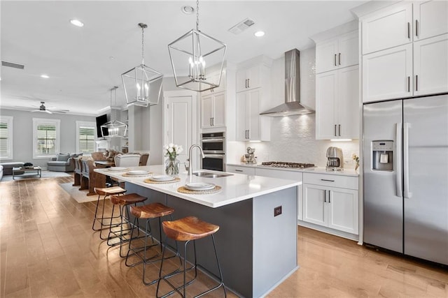 1104 Thomas St, Woodstock, GA 30188 - kitchen with stainless steel appliances, wall chimney exhaust hood, a kitchen breakfast bar, light wood finished floors, and recessed lighting