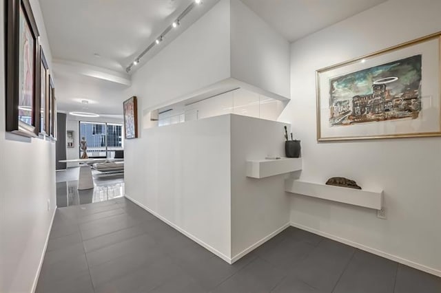 hall featuring track lighting and baseboards