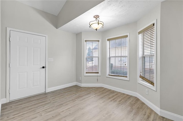 unfurnished room with light hardwood / wood-style flooring and a textured ceiling