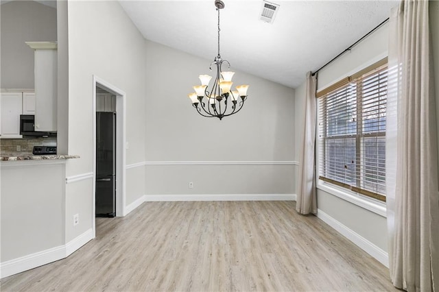 unfurnished dining area featuring light hardwood / wood-style floors, vaulted ceiling, and a chandelier