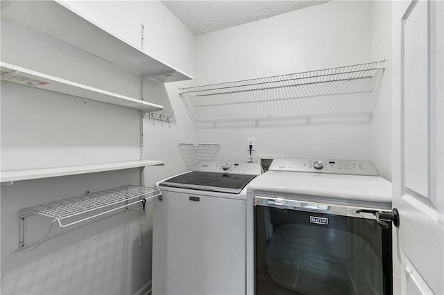 washroom featuring washing machine and dryer and a textured ceiling