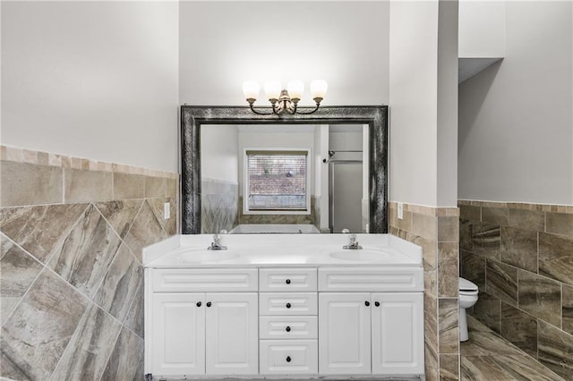 bathroom featuring toilet, tile walls, an inviting chandelier, and vanity