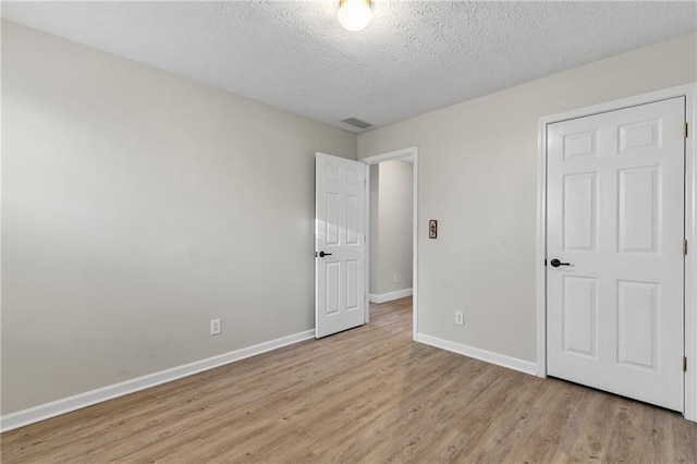 unfurnished bedroom featuring light wood-type flooring and a textured ceiling