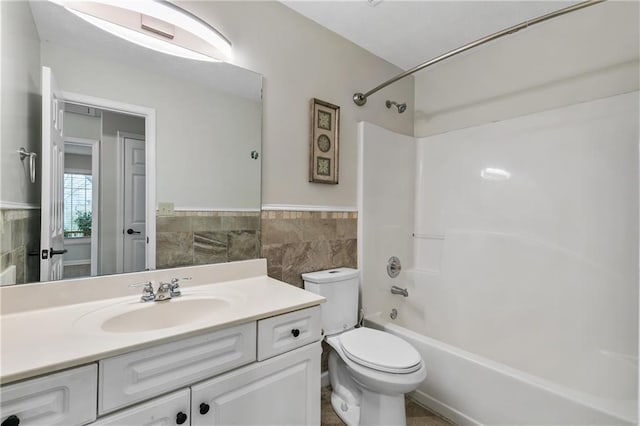 full bathroom featuring tile walls, toilet, vanity, and shower / bathing tub combination