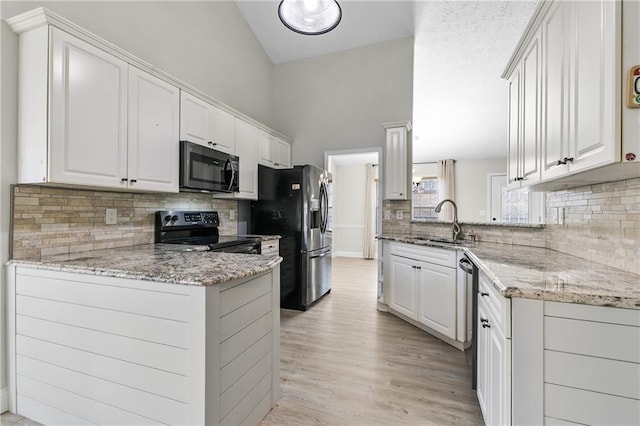 kitchen featuring kitchen peninsula, appliances with stainless steel finishes, white cabinets, and light stone countertops