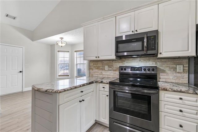 kitchen featuring white cabinets, stainless steel appliances, light stone countertops, and kitchen peninsula