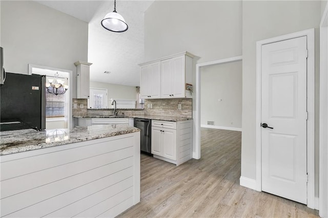 kitchen featuring white cabinets, stainless steel fridge, light stone counters, and dishwasher