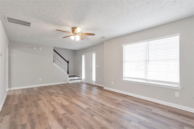 unfurnished living room featuring ceiling fan, a textured ceiling, and light wood-type flooring