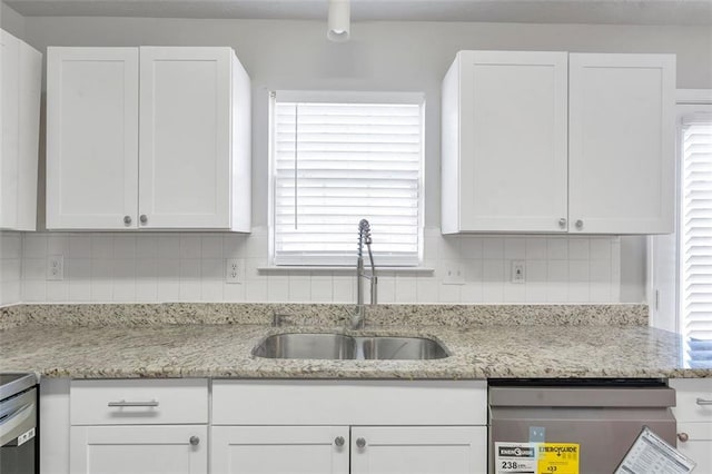 kitchen featuring white cabinets, sink, dishwashing machine, and backsplash