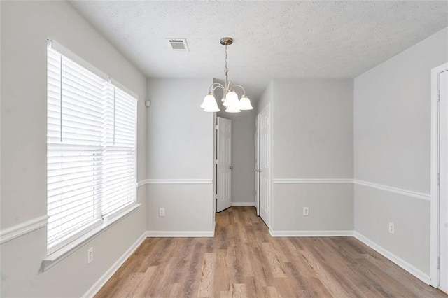 empty room featuring a textured ceiling, plenty of natural light, and a chandelier