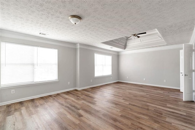 empty room with ceiling fan, hardwood / wood-style floors, ornamental molding, a textured ceiling, and a raised ceiling