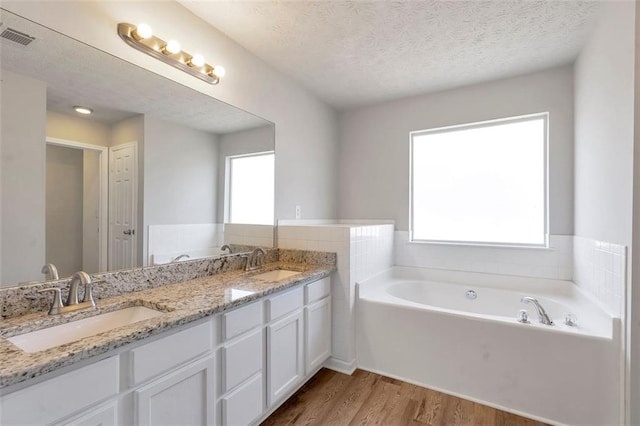 bathroom featuring a bath, vanity, hardwood / wood-style floors, and a textured ceiling