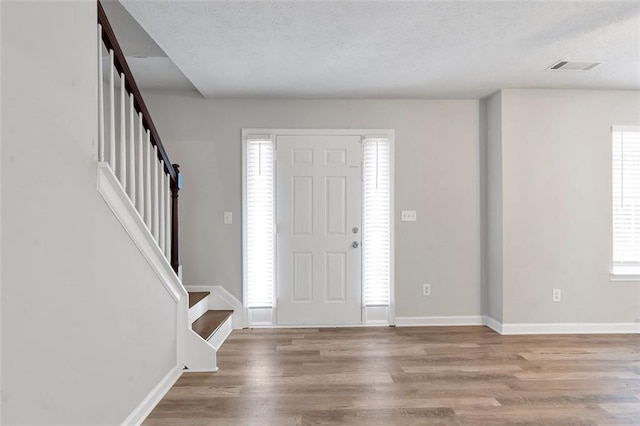 foyer entrance with light hardwood / wood-style floors and a textured ceiling