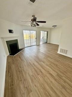 unfurnished living room with a ceiling fan, a fireplace, visible vents, and wood finished floors