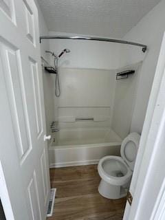 full bathroom featuring toilet, a textured ceiling, shower / washtub combination, and wood finished floors