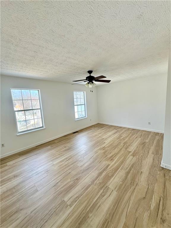 unfurnished room featuring light wood-type flooring, a textured ceiling, baseboards, and a ceiling fan