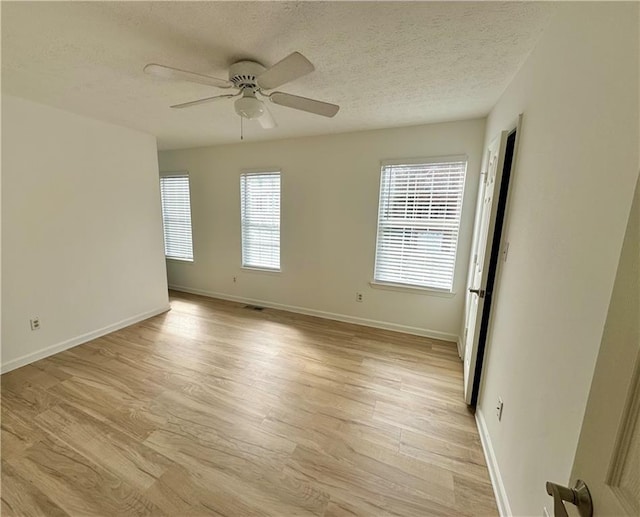 unfurnished room featuring baseboards, ceiling fan, light wood-style flooring, and a textured ceiling