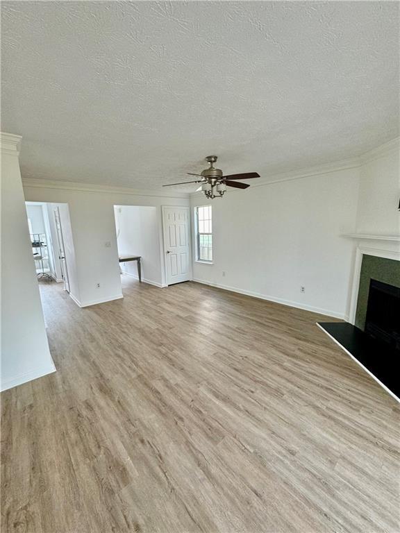 unfurnished living room with a large fireplace, crown molding, and light wood-style floors