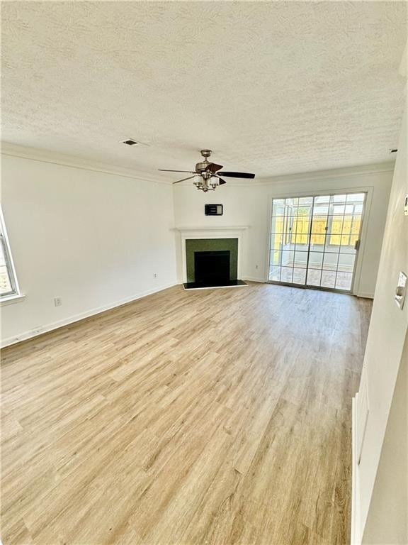 unfurnished living room with light wood finished floors, a fireplace with flush hearth, a ceiling fan, and a wealth of natural light