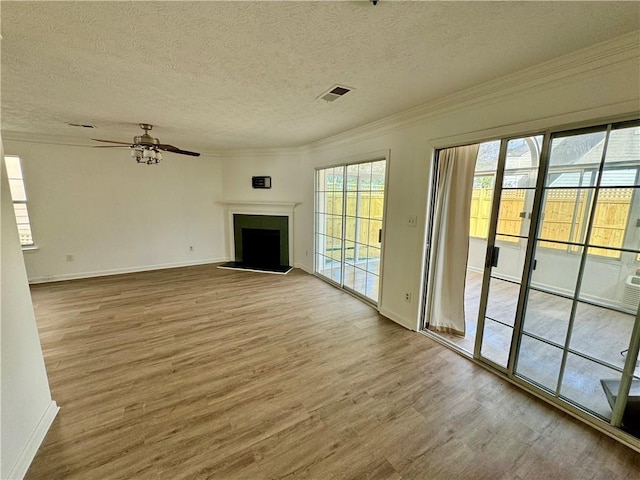 unfurnished living room featuring visible vents, ornamental molding, wood finished floors, a textured ceiling, and a fireplace