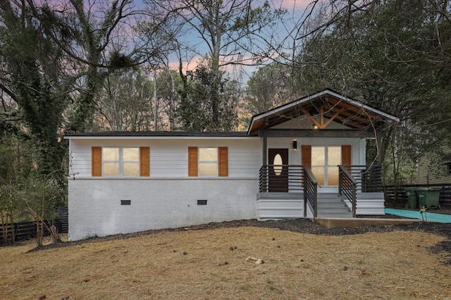 view of front of house with crawl space, covered porch, fence, and brick siding