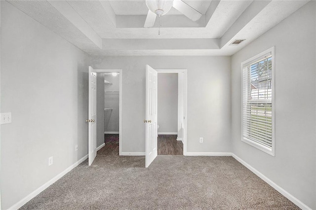 104 Terrapin Ct, Carrollton, GA 30116 - unfurnished bedroom featuring a walk in closet, a tray ceiling, carpet floors, a closet, and baseboards