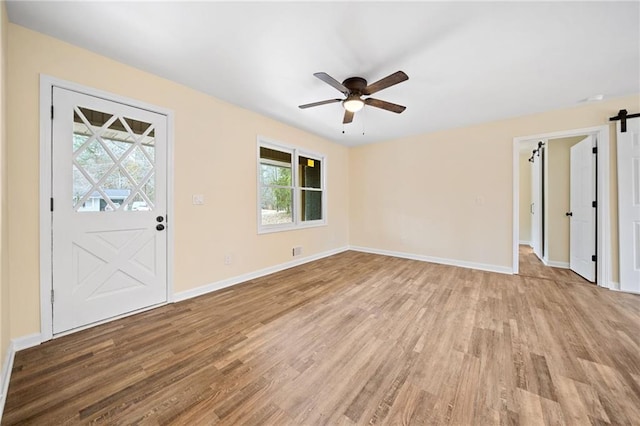 entryway featuring a barn door, a wealth of natural light, ceiling fan, and light wood-type flooring