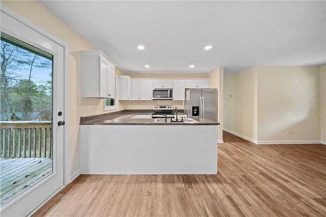 kitchen with kitchen peninsula, light hardwood / wood-style flooring, white cabinets, and stainless steel appliances