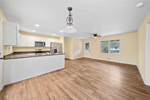 kitchen with white cabinets, decorative light fixtures, light wood-type flooring, and stainless steel appliances