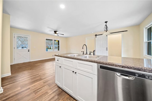 kitchen featuring white cabinetry, dishwasher, sink, a barn door, and light hardwood / wood-style flooring