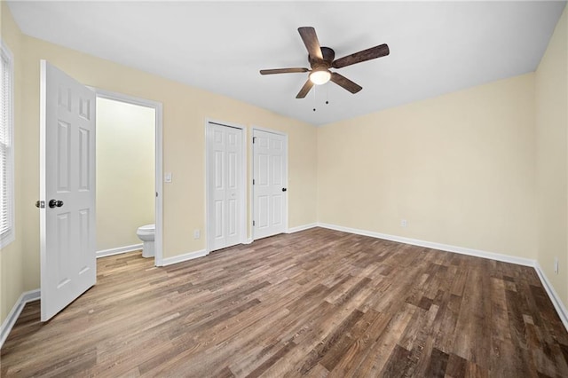 unfurnished bedroom with connected bathroom, multiple closets, ceiling fan, and wood-type flooring