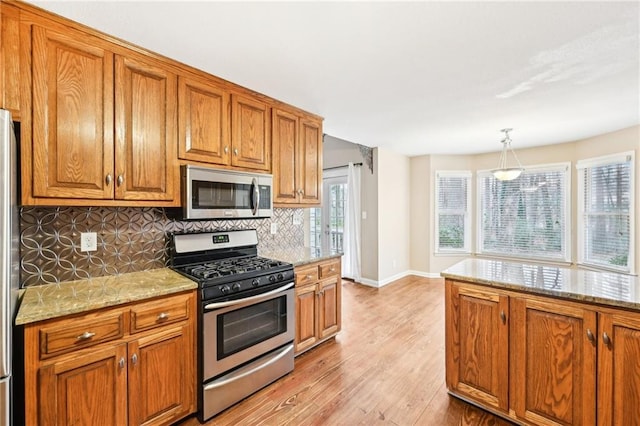 105 Spring Forest Way, Sharpsburg, GA 30277 - kitchen featuring light stone counters, decorative light fixtures, tasteful backsplash, appliances with stainless steel finishes, and brown cabinetry