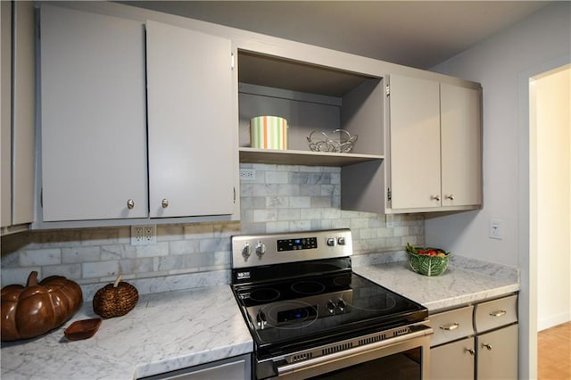 kitchen featuring electric stove, light stone countertops, and backsplash