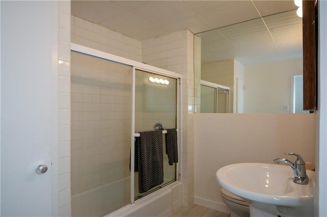 full bathroom with combined bath / shower with glass door, sink, and toilet