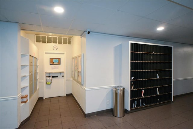 corridor with dark tile patterned floors and a drop ceiling