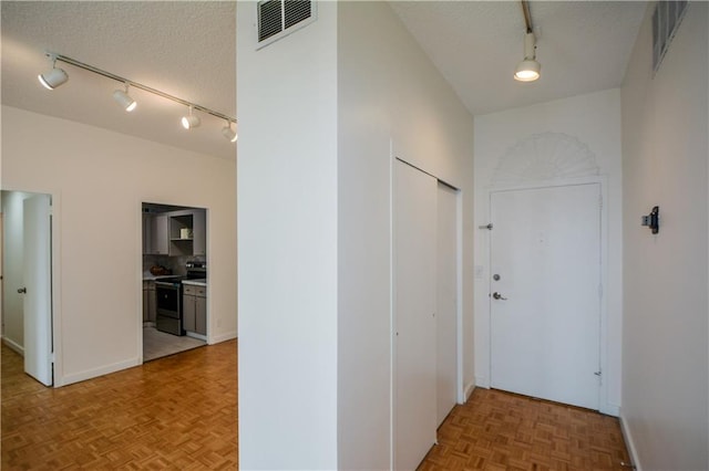 hall featuring parquet floors, track lighting, and a textured ceiling