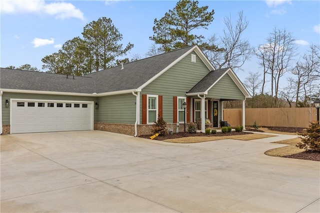 view of front facade with driveway, fence, roof with shingles, a garage, and brick siding