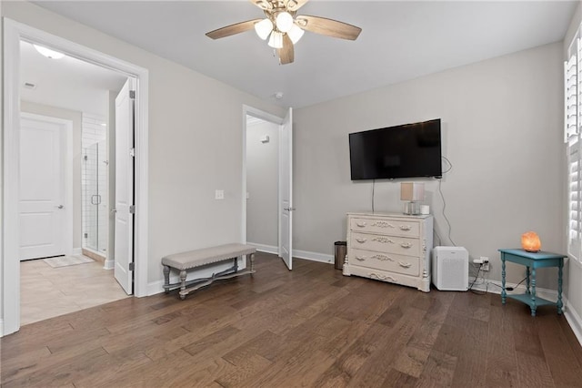 bedroom with ceiling fan, connected bathroom, baseboards, and wood finished floors