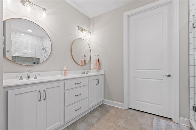 bathroom with double vanity, tile patterned flooring, baseboards, and a sink