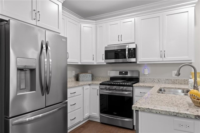 kitchen with light stone counters, white cabinetry, stainless steel appliances, and a sink