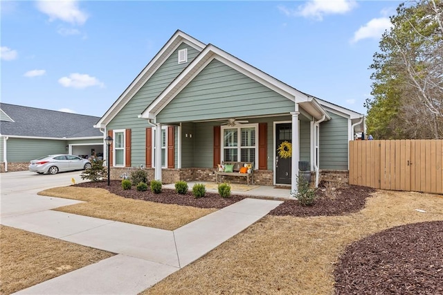 view of front of house featuring brick siding, covered porch, ceiling fan, and fence