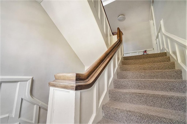 staircase featuring a wainscoted wall and a decorative wall