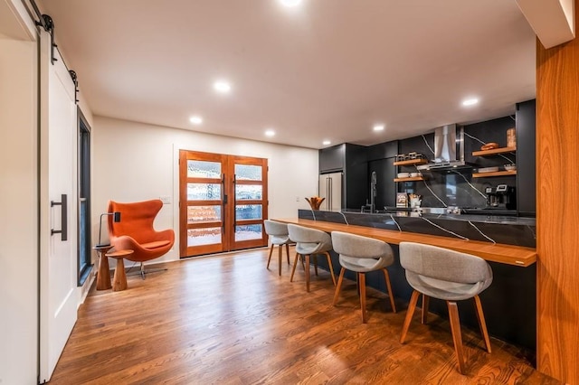 bar featuring sink, high end fridge, a barn door, dark wood-type flooring, and french doors