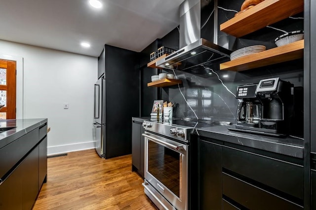 kitchen with tasteful backsplash, extractor fan, light hardwood / wood-style floors, and premium appliances