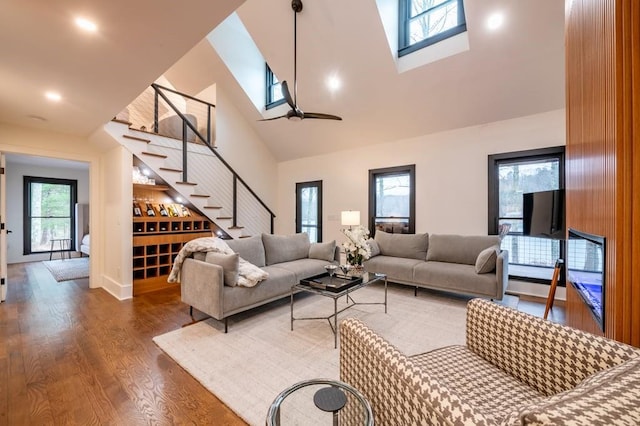 living room with hardwood / wood-style floors, a skylight, and high vaulted ceiling