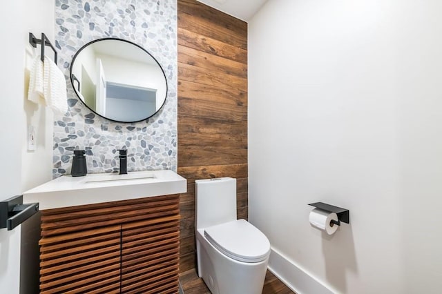 bathroom featuring hardwood / wood-style flooring, wooden walls, vanity, and toilet