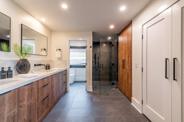 bathroom featuring a shower with door, vanity, tile patterned floors, and toilet