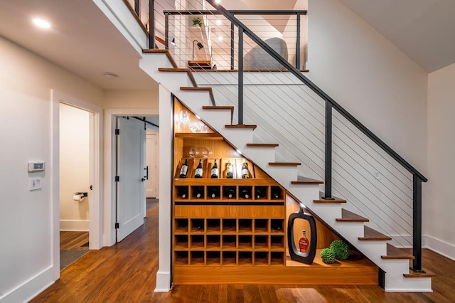 wine room featuring dark wood-type flooring and a towering ceiling